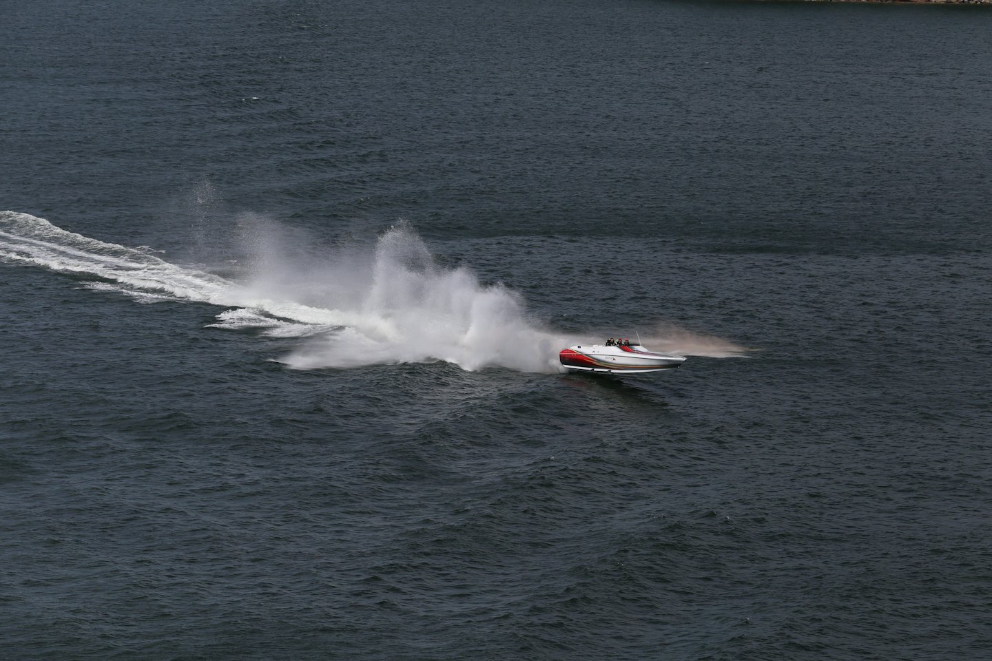 White and red speedboat racing across blue water.