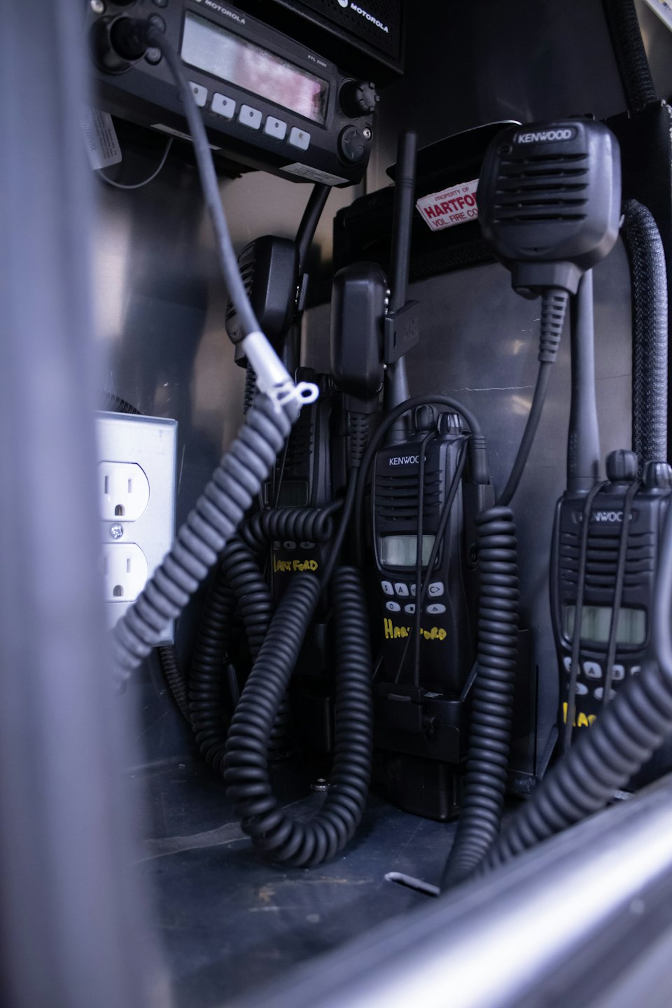Emergency communication equipment stored inside a metal compartment.