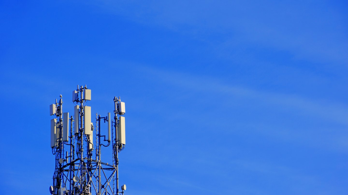 A tall metal telecommunications tower stands against a clear sky.