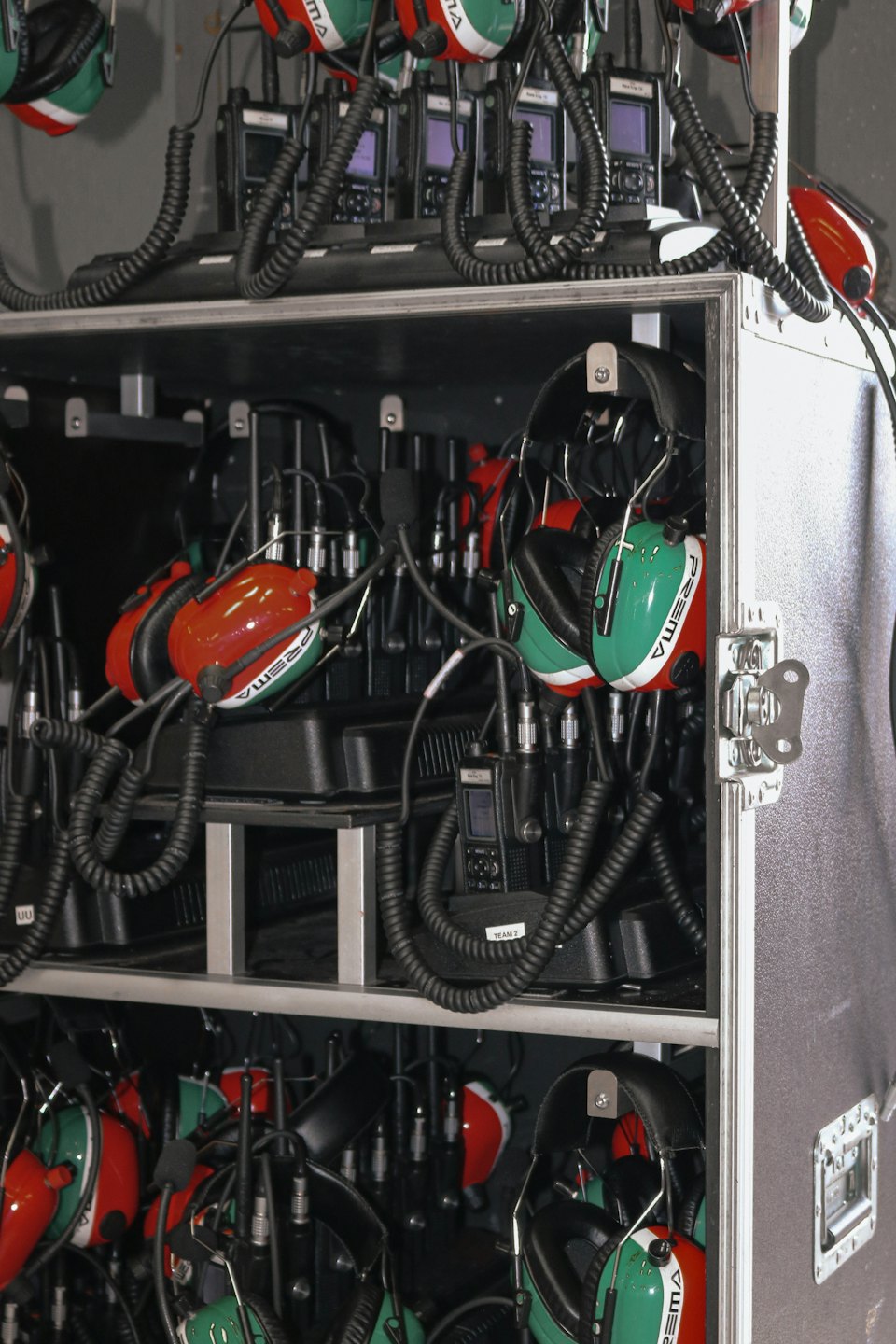 Colorful two-way radios and headsets organized on a metal rack.